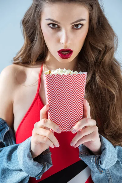 Surprised sexy girl holding popcorn and looking at camera — Stock Photo