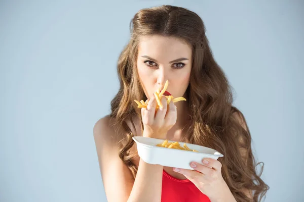 Sexy Mädchen im roten Badeanzug isst Pommes Frites isoliert auf grau — Stockfoto