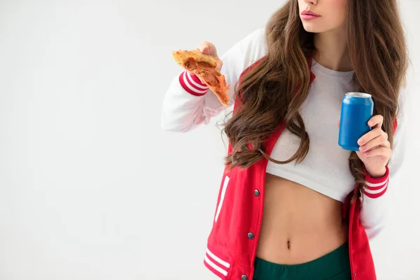 Обрезанный образ сексуальной девушки в бейсбольной куртке проведение пиццы и банки изолированы на белом — стоковое фото