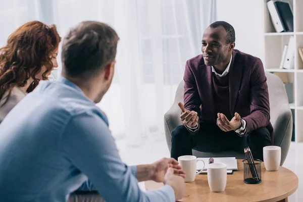 Sorridente consulente afro-americano che parla con una giovane coppia in carica — Foto stock