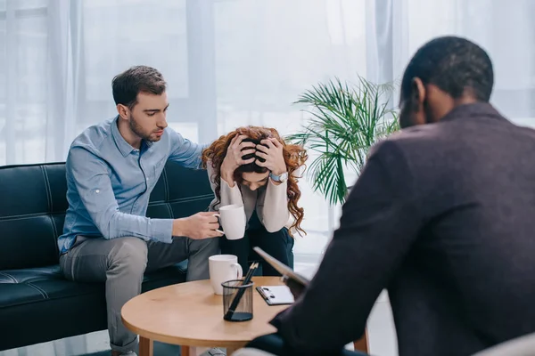 Giovane uomo abbracciare la ragazza frustrato e consulente con il libro di testo — Foto stock