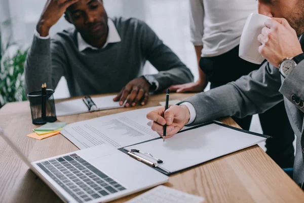 Conseiller financier boire du café et écrire pendant que les clients attendent — Photo de stock