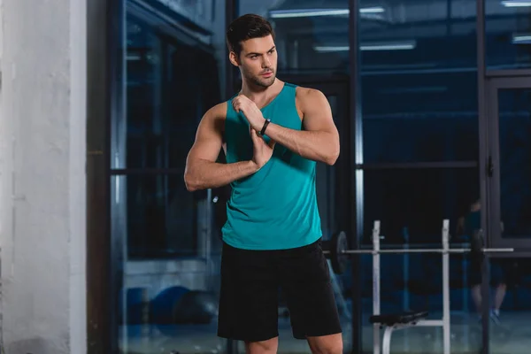 Apuesto deportista estirando brazos en gimnasio - foto de stock