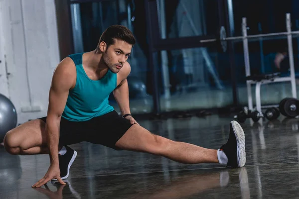 Deportista estirando piernas en sala de deportes - foto de stock