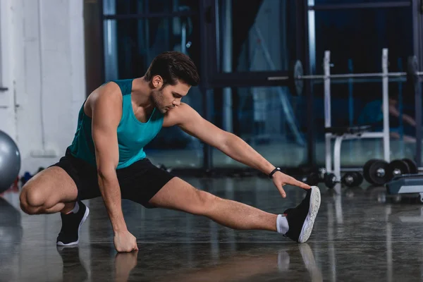 Deportista estirando piernas en centro deportivo - foto de stock