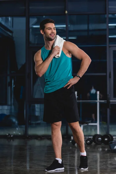Deportista sonriente de pie con toalla después del entrenamiento en el gimnasio - foto de stock
