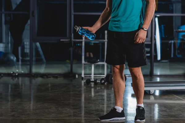 Vue recadrée d'un sportif tenant une bouteille de sport dans une salle de sport — Photo de stock