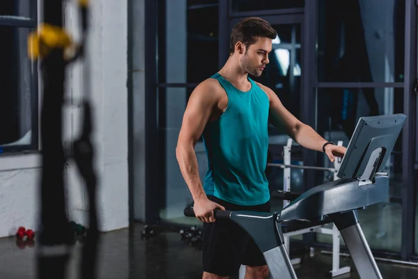 Apuesto deportista entrenamiento en la cinta de correr en el gimnasio — Stock Photo