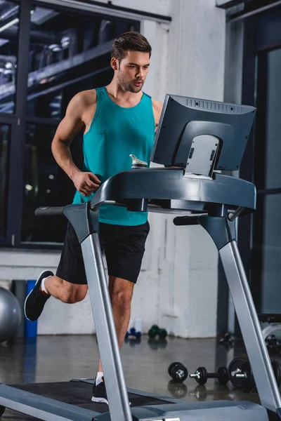 Athletic man running on treadmill in sports center — Stock Photo