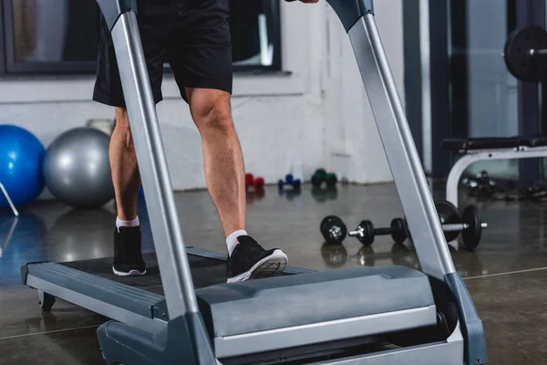 Low section view of sportsman in sneakers jogging on treadmill in gym — Stock Photo