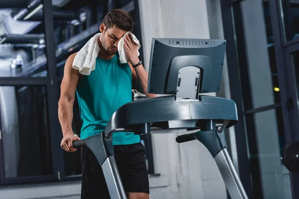 Tired sweaty sportsman with towel training on treadmill in gym — Stock Photo