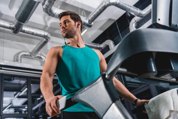 Bottom view of sportsman listening music and training on treadmill in gym — Stock Photo