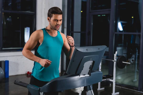 Sportsman jogging on treadmill in sports hall — Stock Photo