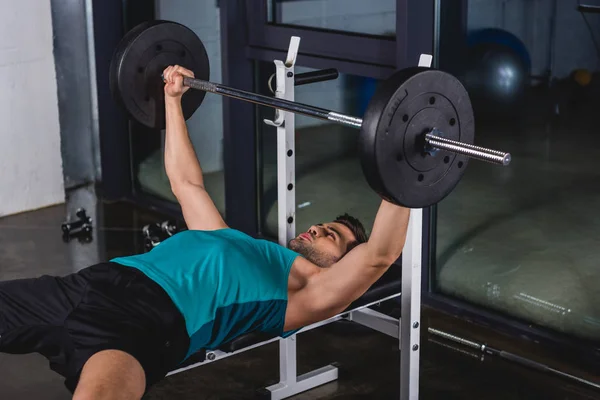 Forte sportivo che esercita con bilanciere in palestra — Foto stock