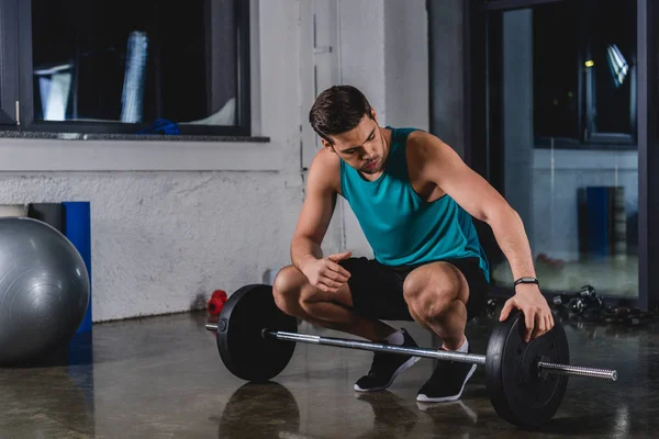 Schöner Sportler mit Langhantel in Sporthalle — Stockfoto