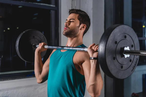 Sportsman lifting barbell in sports hall — Stock Photo