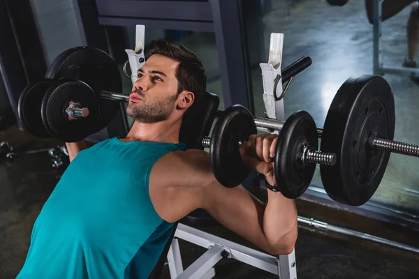 Muscular sporty man exercising with dumbbells in gym — Stock Photo