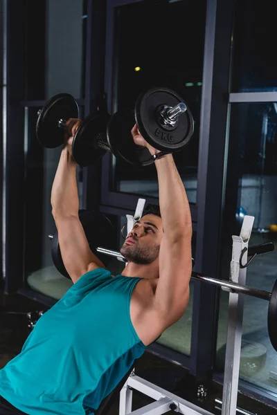 Muscular sportsman exercising with dumbbells in gym — Stock Photo