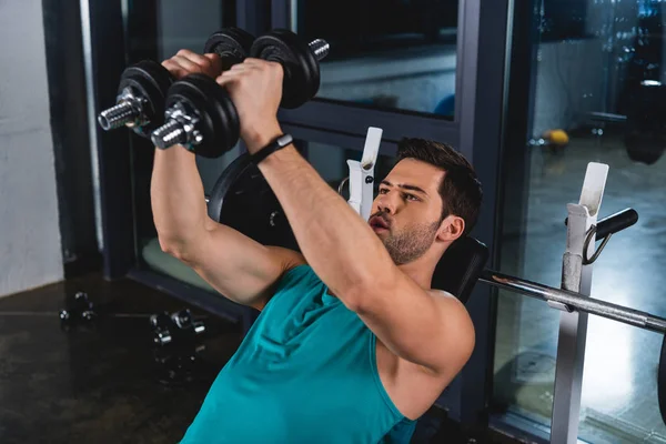 Musculoso deportista fuerte ejercitando con pesas en pabellón deportivo - foto de stock