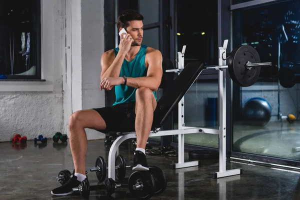 Sportler ruht sich aus und nutzt Smartphone im Fitnessstudio — Stockfoto