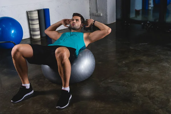 Sportsman doing abs on fit ball in sports hall — Stock Photo