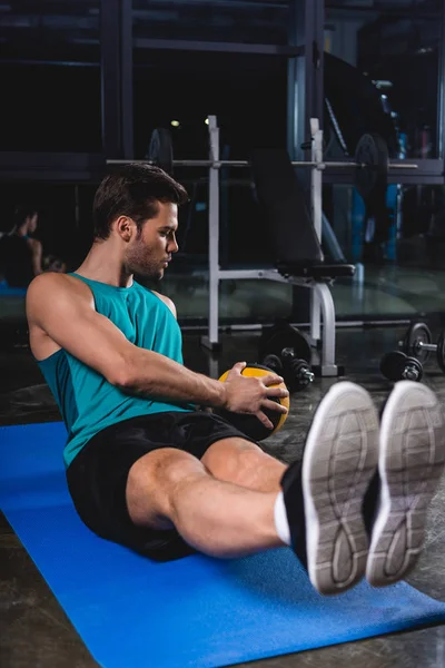 Entrenamiento de deportista con balón de medicina en estera de yoga en centro deportivo - foto de stock