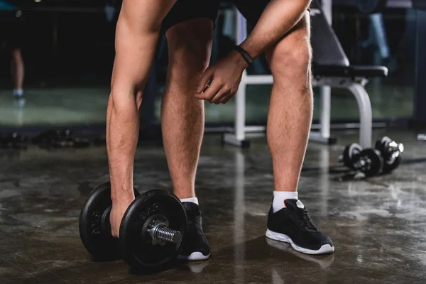 Cropped view of sportsman training with dumbbell in gym — Stock Photo