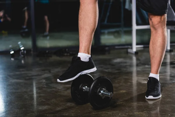 Низкий вид секции спортсмена, стоящего с гантелями в спортзале — Stock Photo