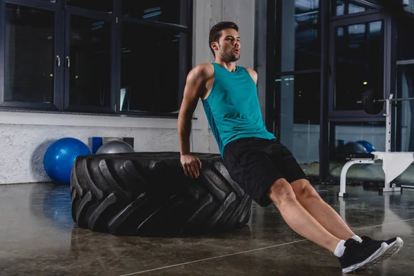 Deportista haciendo flexiones en neumático en gimnasio - foto de stock