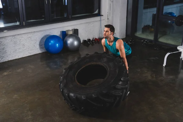 Desportista levantar pneu durante o treinamento cruzado no ginásio — Fotografia de Stock