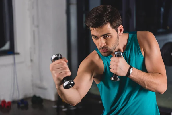 Sporty man training with dumbbells in sports center — Stock Photo