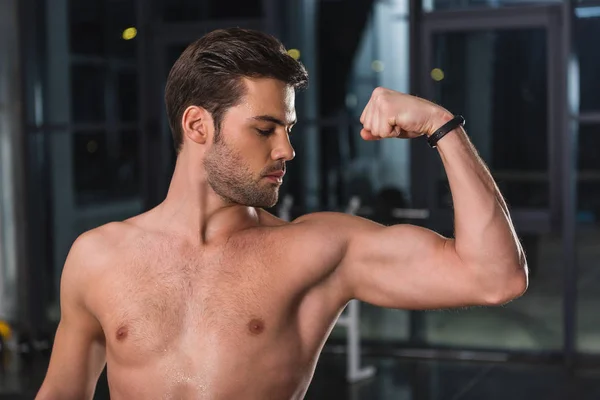 Sin camisa apuesto deportista mostrando los músculos en el gimnasio - foto de stock