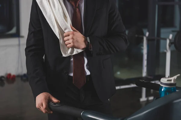 Cropped view of businessman with towel training on treadmill in sports center — Stock Photo