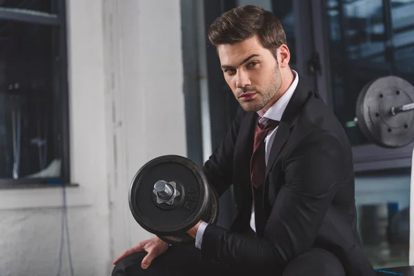 Handsome businessman in suit training with dumbbell in sports center — Stock Photo
