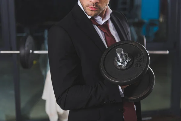 Vue recadrée de l'homme d'affaires sportif en costume d'entraînement avec haltère dans la salle de gym — Photo de stock