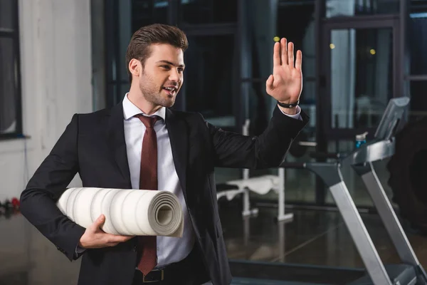 Manager waving and holding yoga mat in sports hall — Stock Photo