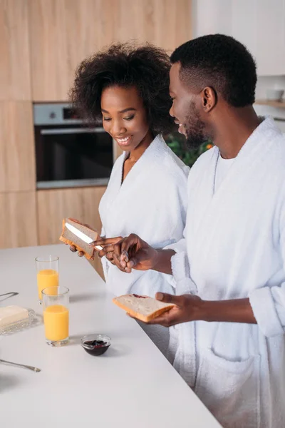 Joven pareja afroamericana desayunando en la cocina - foto de stock