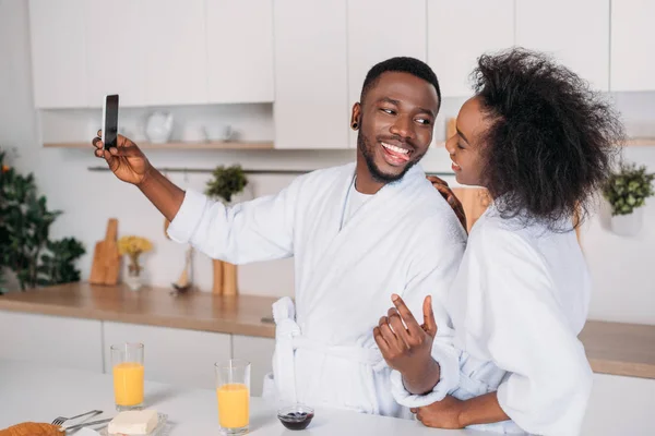 Sonriente pareja afroamericana tomando selfie en cocina - foto de stock