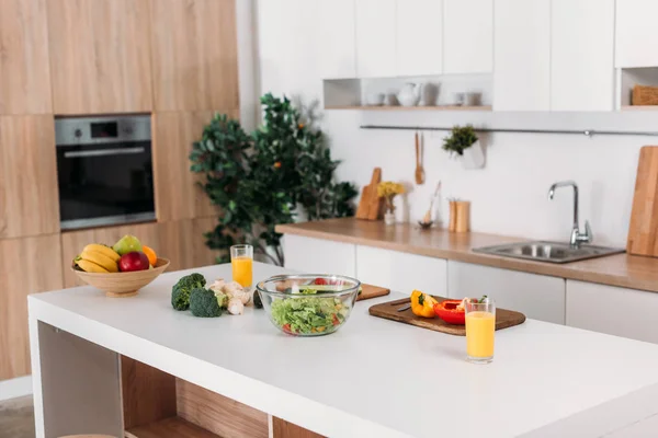 Interieur der modernen Küche mit Gemüse, Obst und Salat auf dem Tisch — Stockfoto