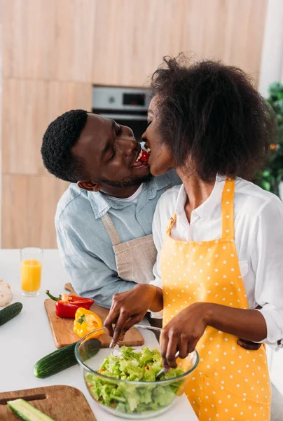 Junges Paar isst Kirschtomaten und mischt Salat in Schüssel — Stockfoto