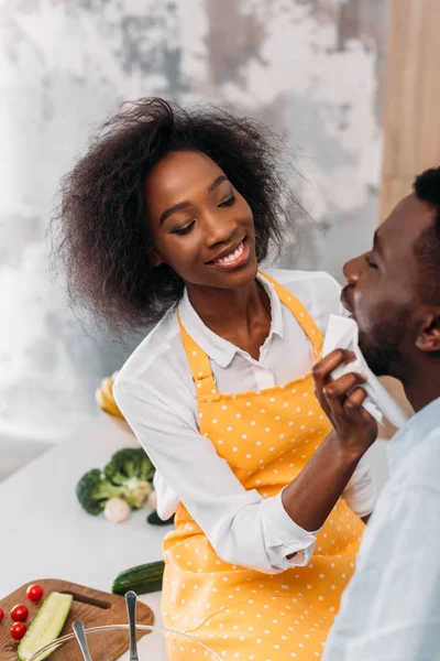 Sonriente afroamericano limpiando boca de novio por servilleta - foto de stock