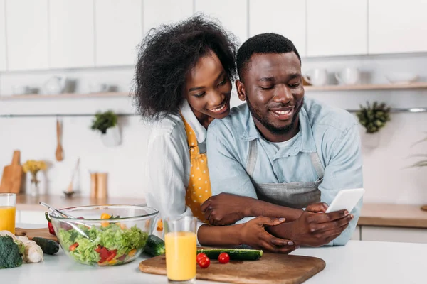 Jeune homme tapant sur smartphone et petite amie debout derrière — Photo de stock