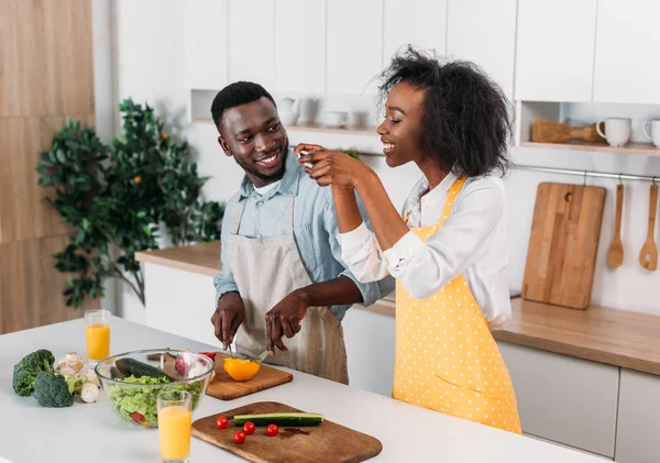 Lächelnde Frau fotografiert Essen am Tisch, während ihr Freund Pfeffer schneidet — Stockfoto