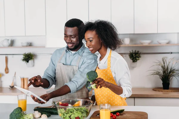 African american couple looking at recipe on digital tablet — Stock Photo