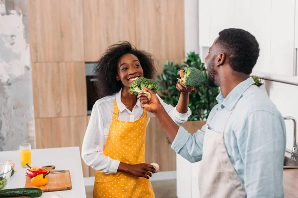 Lächelndes Paar hat Spaß mit Brokkoli in der Küche — Stockfoto