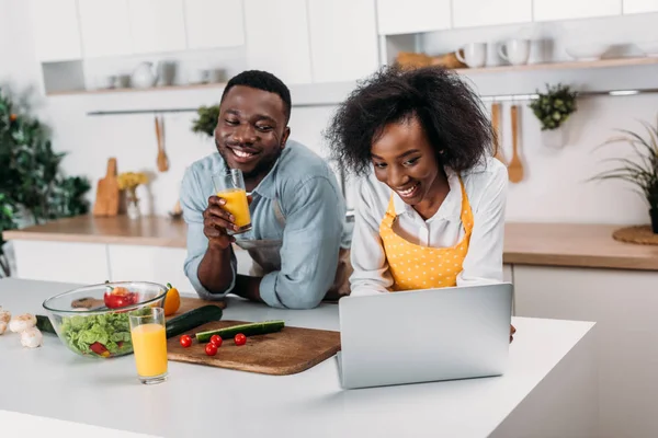 Африканская американская пара веселится с ноутбуком на кухне — стоковое фото