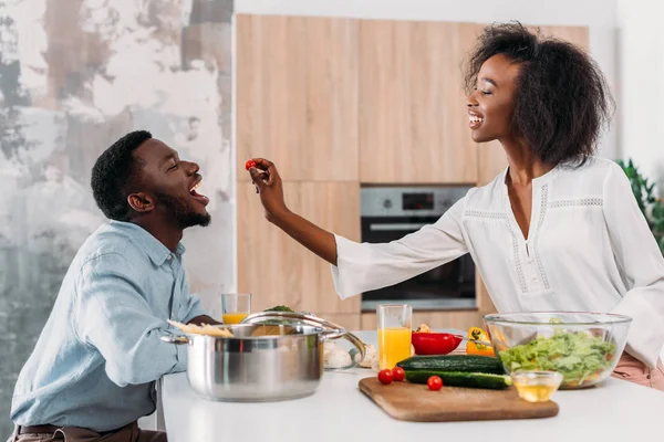 Side view of smiling woman giving cherry tomato to boyfriend — Stock Photo