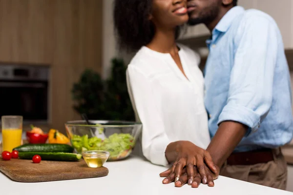 Vista cortada do casal afro-americano à mesa com salada, óleo e legumes — Fotografia de Stock
