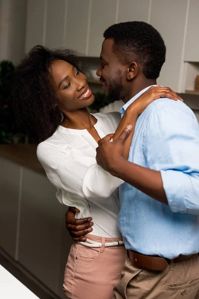 Jeune couple afro-américain souriant dansant dans la cuisine — Photo de stock