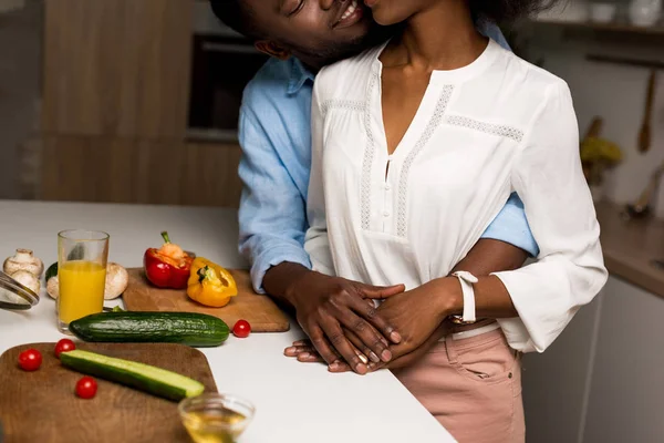 Cropped image of young african american couple hugging near table with vegetables — Stock Photo